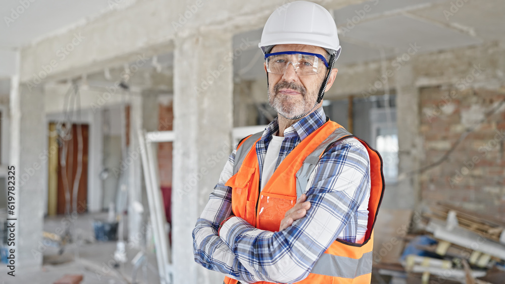 Middle age man builder standing with arms crossed gesture and relaxed expression at construction site Middle age man builder standing with arms crossed gesture and relaxed expression at construction site
