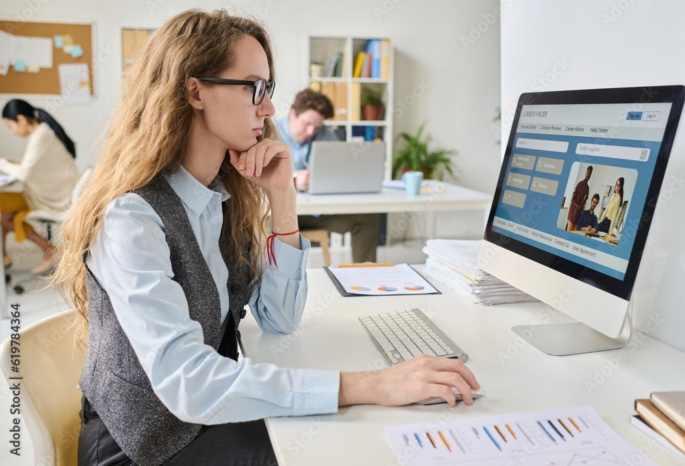 Businesswoman sitting at her workplace and using computer to search for the new job Businesswoman sitting at her workplace and using computer to search for the new job