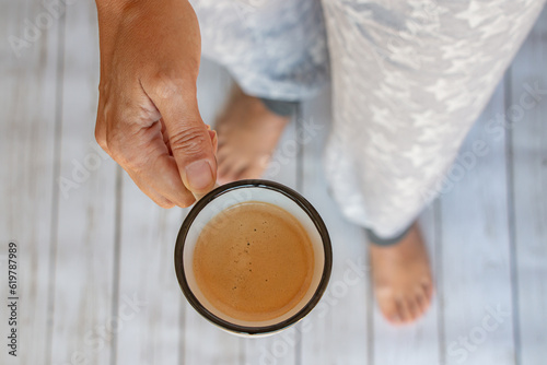 taza de café con espuma en manos de una mujer, vista cenital photo