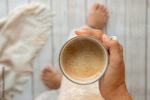 taza de café con espuma en manos de una mujer, vista cenital photo