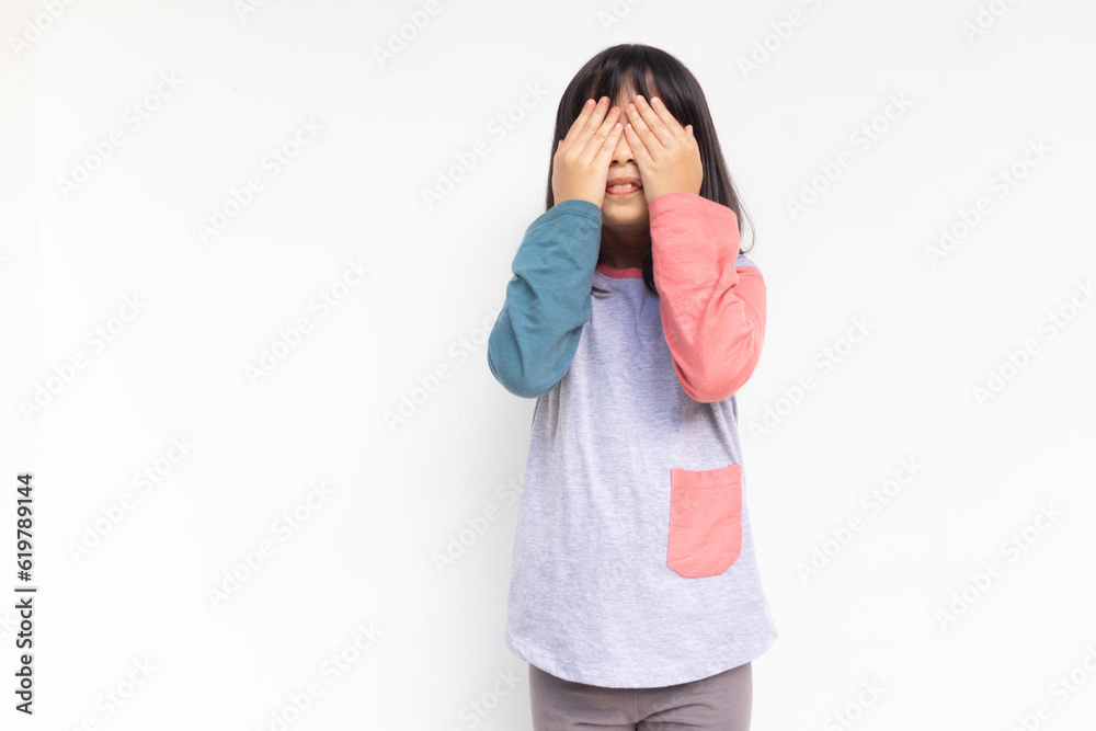 A cute smiling girl covering his eyes, playing hide and seek A cute smiling girl covering his eyes, playing hide and seek