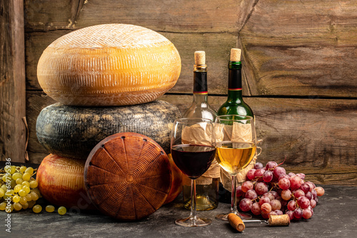 Fototapeta Naklejka Na Ścianę i Meble -  Glass of wine, cheeses and grapes on a wooden background, A head of hard cheese, Long banner format