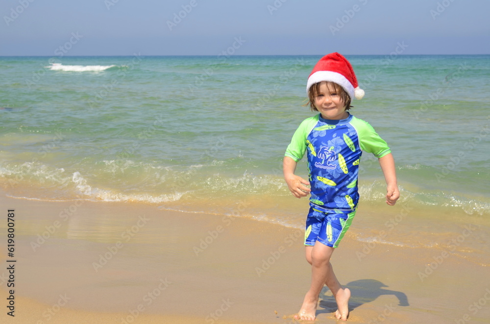 Christmas family vacation on tropical island. Boy in Santa hat playing in beach on family vacation. Christmas at the seaside resort. Family travel, winter holidays at sea