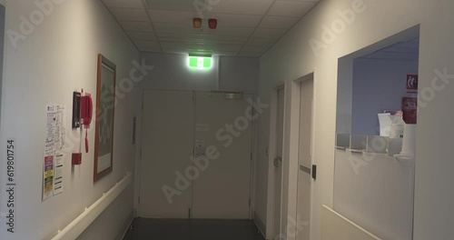 Hospital hallway camera pans up to reveal maternity rooms sign. 