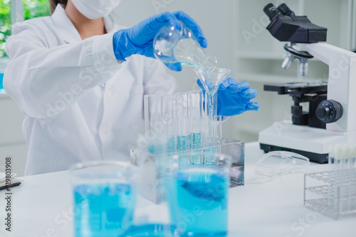 Close up of Female scientist or researcher is pouring blue substance or liquid in to a sample test tube. Concept of science  biochemistry  chemical  biotechnology laboratory. Analyzing and experiment