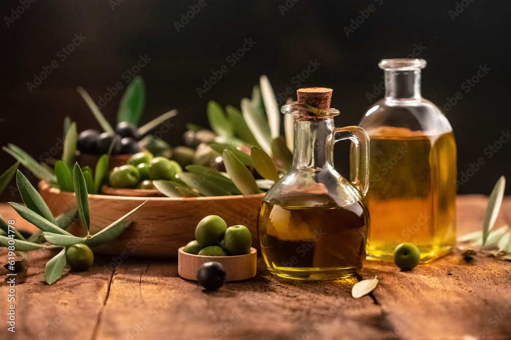 Olive oil in bottles with black and green olives and leaves. extra virgin olive oil jars on a wooden background. place for text Olive oil in bottles with black and green olives and leaves. extra virgin olive oil jars on a wooden background. place for text