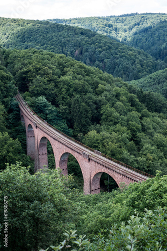 old arch Bridge railway viaduct between hills in the green Forest Germany trees