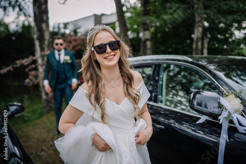 A happy bride wearing sunglasses walks ahead of the grooms