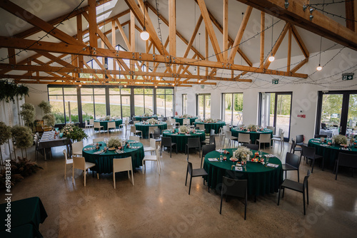 The venue is decorated for a wedding with round tables and green tablecloths, it looks unique and beautiful photo