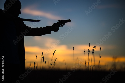 Silhouette of a demon and vampire hunter with a dramatic sky in the background. A man with a katana and a revolver. Fantasy and halloween concept