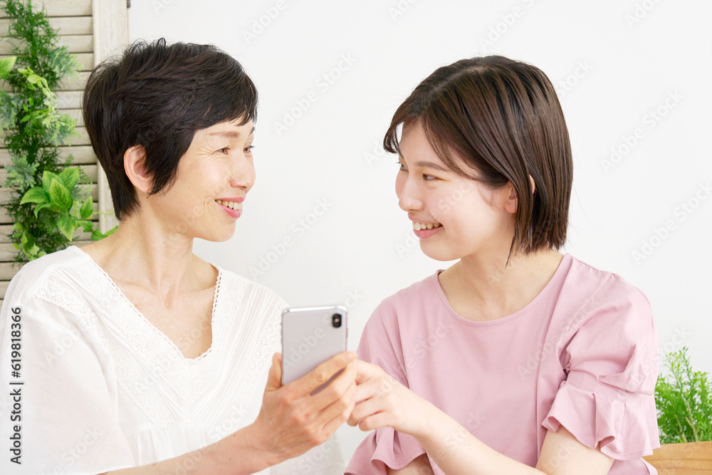 自宅でスマホを使う母親と娘 自宅でスマホを使う母親と娘