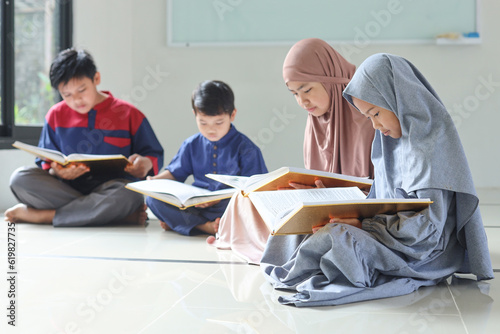 Group of Asian Muslim children reciting Koran or Quran together in a mosque during Ramadhan. Selective focus photo