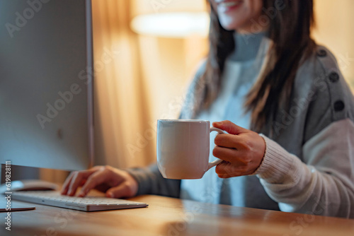 Closeup hand of woman holding coffee cup, Smiling female entrepreneur working from home late at night