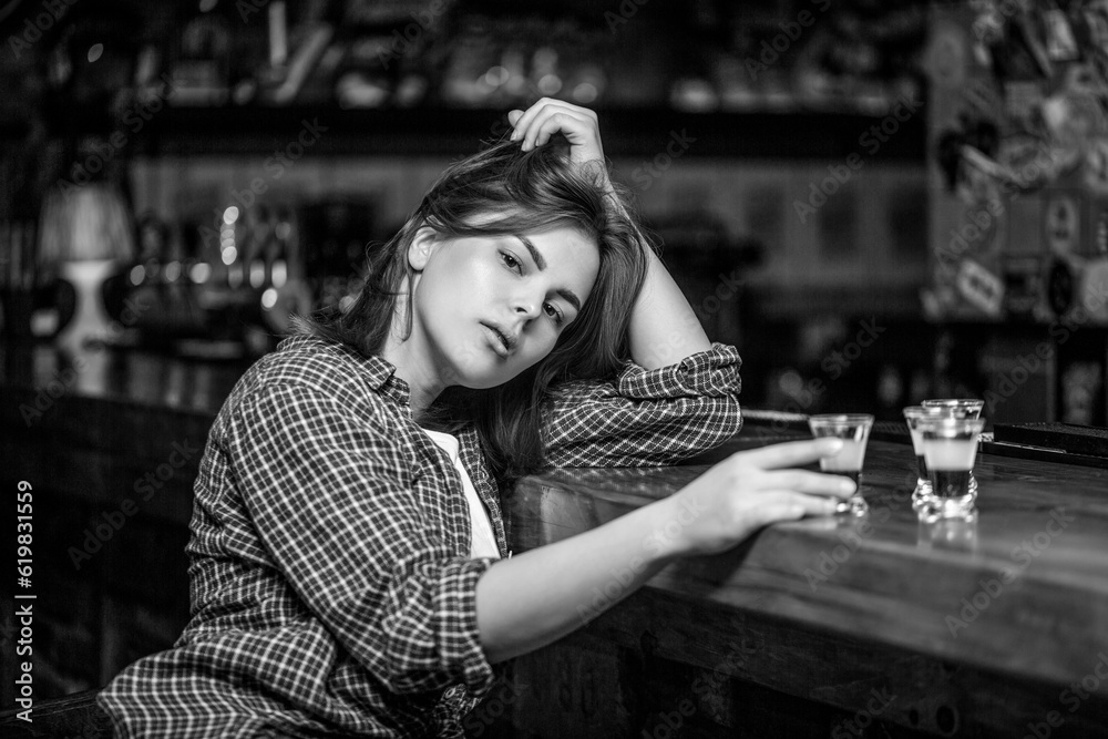 Woman drinking alcohol. Scotch whiskey glass isolated at bar or pub in alcohol abuse and alcoholic concept. Black and white