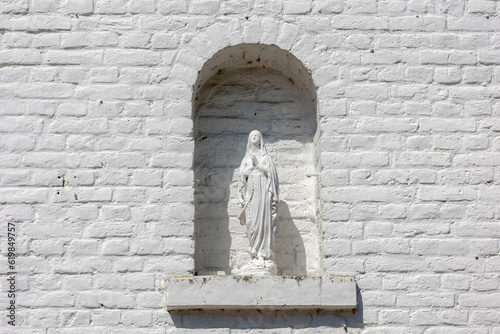 Saint Mary statue in the white bricks wall, A first-century Jewish woman of Nazareth, The wife of Joseph and the mother of Jesus, She is a central figure of Christianity, Limburg province, Netherlands photo