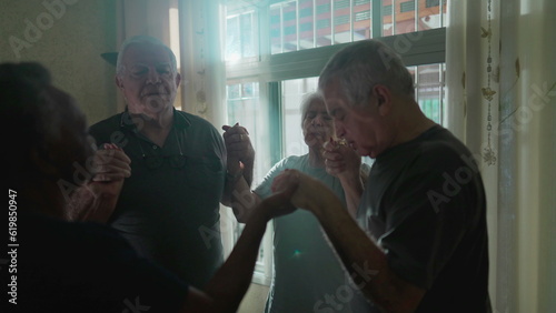 Принти на полотні Devoted Elderly Group Praying at Home with Sunlight Streaming Through Window