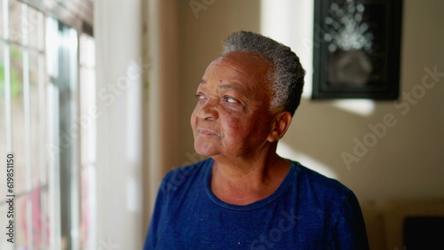 Foto Contemplative Senior woman stands by window staring outside at home