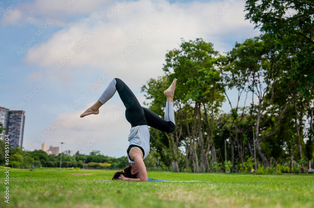 Indian girl in sportswear practicing yoga poses posing with legs raised on mat in park Indian girl in sportswear practicing yoga poses posing with legs raised on mat in park
