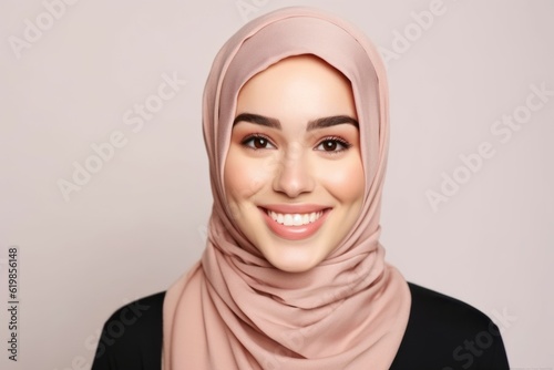 Portrait of beautiful young muslim woman with hijab smiling on grey background photo