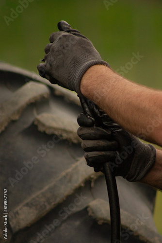 Gloved Man Hands Fixing Tractor Hydraulic Hose with Tire Background