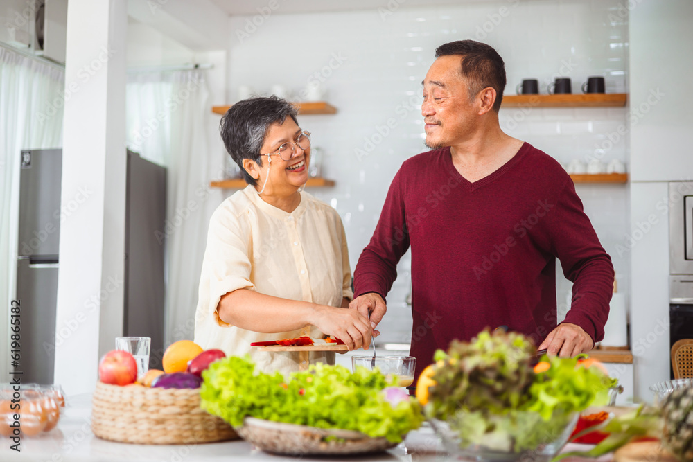 Asian elderly couple cooking in kitchen to prepare dinner