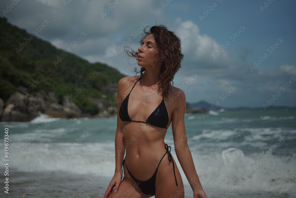 Beautiful girl in a black bikini on the seashore.