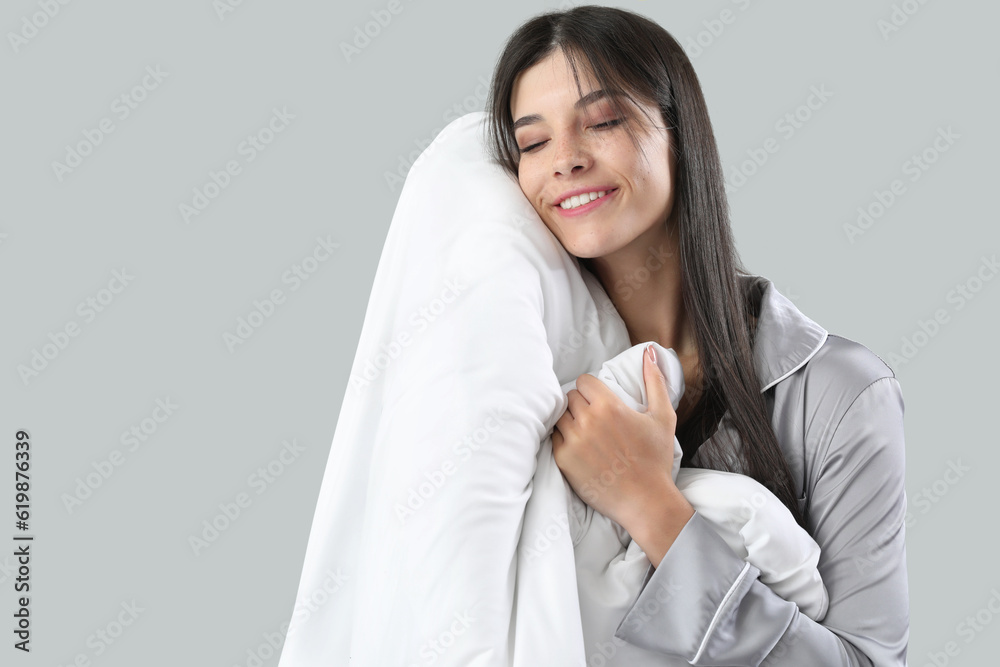 Beautiful happy young woman with soft blanket sleeping on grey background Beautiful happy young woman with soft blanket sleeping on grey background