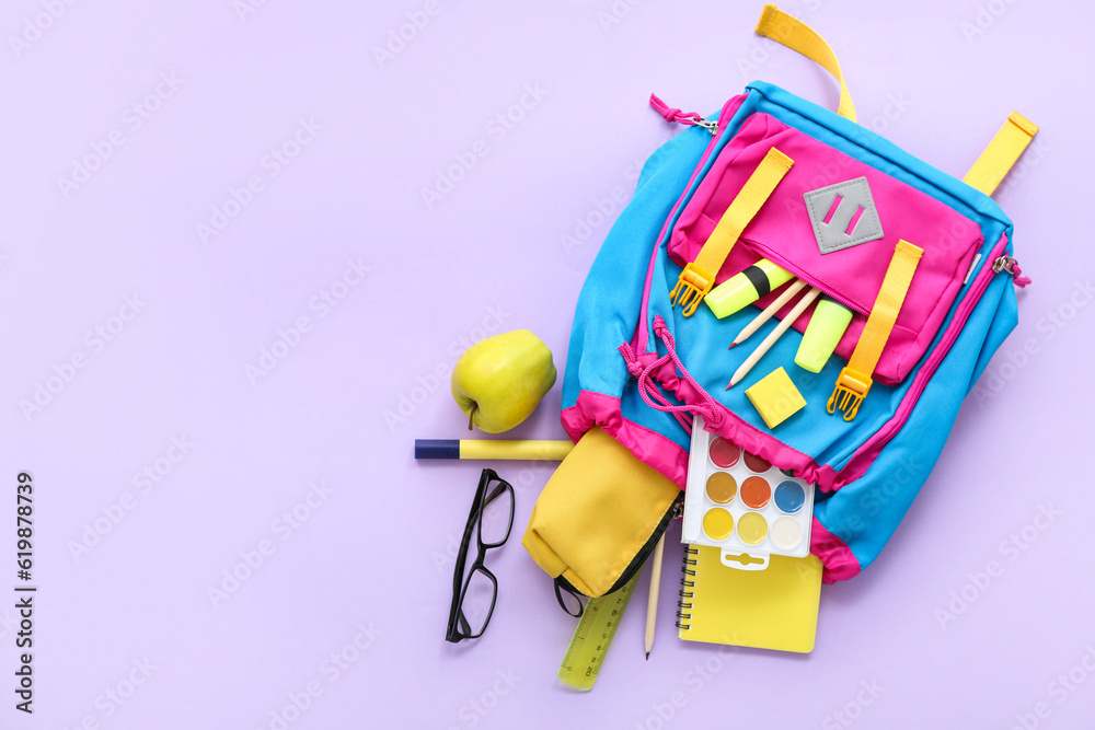 Color school backpack with pencil case, eyeglasses and apple on lilac background Color school backpack with pencil case, eyeglasses and apple on lilac background