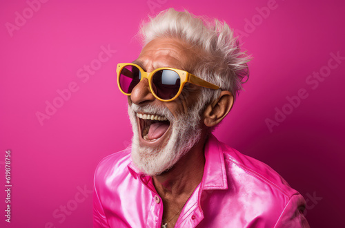 senior male, smiling, dressed in pink and sunglasses on a pink background. Generative AI © Fabrizio