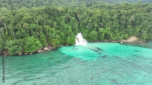 The scenic Momon waterfall tumbles from the primordial rainforest of West Papua into the shallow sea. This spectacular waterfall is found about a day's sail north of Kaimana.   photo