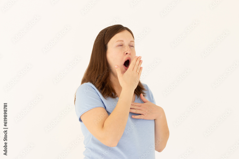 Tired woman yawning covering open mouth with hand need rest. Young female worker being sleepy head can't wake up having insomnia. Chain reaction Tired woman yawning covering open mouth with hand need rest. Young female worker being sleepy head can't wake up having insomnia. Chain reaction