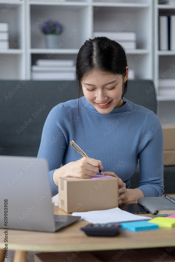 Asian woman online store business owner, online shop owner working from home, posting products for sale on website and accepting orders and packing products for customers with private courier service. Asian woman online store business owner, online shop owner working from home, posting products for sale on website and accepting orders and packing products for customers with private courier service.