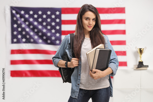 Female student with a backpack and books in front of USA flag