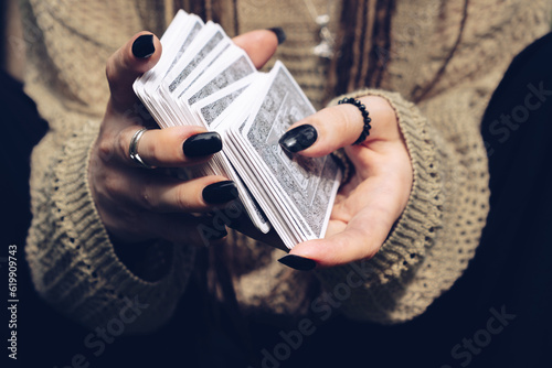 Fotografía close up hands holding a deck of Tarot cards, black nails