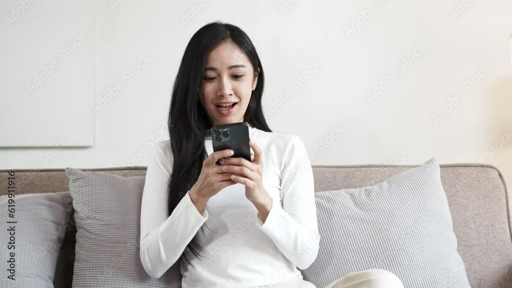 Happy young asian woman relax on comfortable couch at home texting messaging on smartphone, smiling girl use cellphone, chatting online message, shopping online from home Happy young asian woman relax on comfortable couch at home texting messaging on smartphone, smiling girl use cellphone, chatting online message, shopping online from home