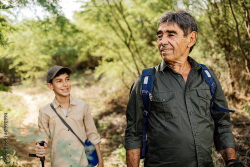 Grandfather and pre-teen grandson hiking in nature, with the elder sharing his knowledge and experience