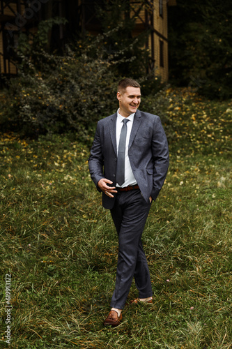 portrait of the groom outside in the autumn season.stylish tall groom in a blue suit.businessman in nature. portrait of a successful man