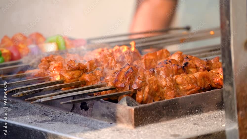 slow motion shot of tikka kebabs cooking over coal fire with smoke steam coming off showing a popular street food in delhi, lucknow india with chicken and mutton slow motion shot of tikka kebabs cooking over coal fire with smoke steam coming off showing a popular street food in delhi, lucknow india with chicken and mutton