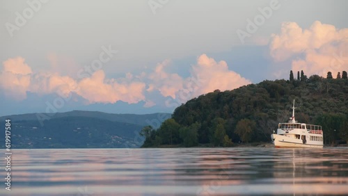 View of the Calm Lake Water Suface, Hills and Passing Riverboat in Soft Evening Light photo