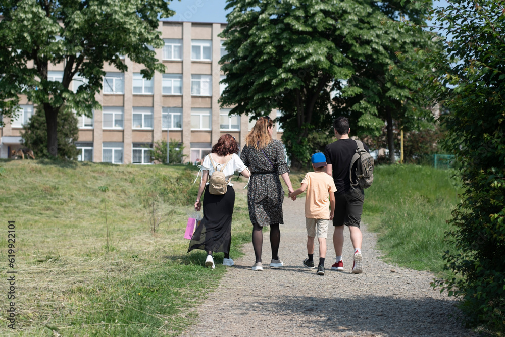 A woman with three children of different ages are walking to the city center on a bad unpaved road, everyone is holding hands, children love their mother very much, rear view A woman with three children of different ages are walking to the city center on a bad unpaved road, everyone is holding hands, children love their mother very much, rear view