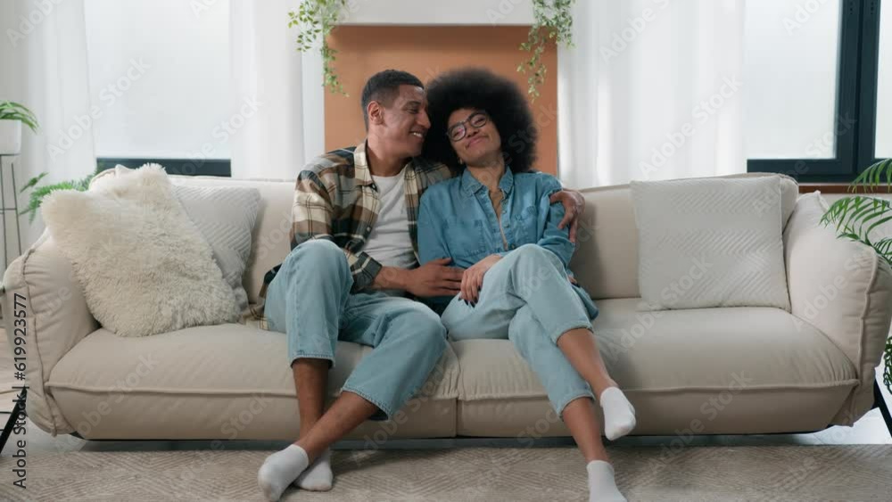 Happy family African American couple in love hugging at couch at home spending time together affectionate bonding man husband boyfriend woman wife girlfriend cuddling hug homeowners estate renters Happy family African American couple in love hugging at couch at home spending time together affectionate bonding man husband boyfriend woman wife girlfriend cuddling hug homeowners estate renters