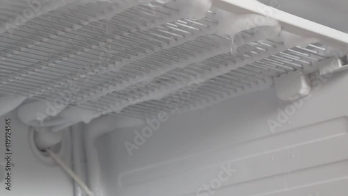 Defrosting the refrigerator from ice . Cleaning, a lot of ice and snow melts in the freezer of the refrigerator. Drops of ice are dripping. Cleaning the refrigerator. A broken household appliance.