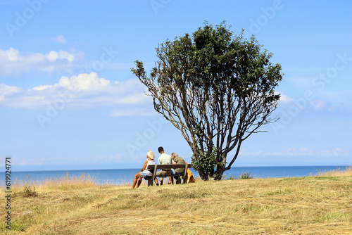 Natural and sea landscape. Family sits on a bench and looks at the sea.