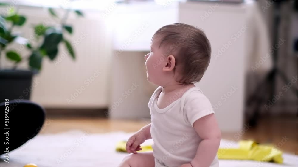 Chubby little boy in white bodysuit sitting on fluffy rug laid on floor in nursery barefoot baby pointing gesturing with hand relaxing at home happy childhood and development Chubby little boy in white bodysuit sitting on fluffy rug laid on floor in nursery barefoot baby pointing gesturing with hand relaxing at home happy childhood and development