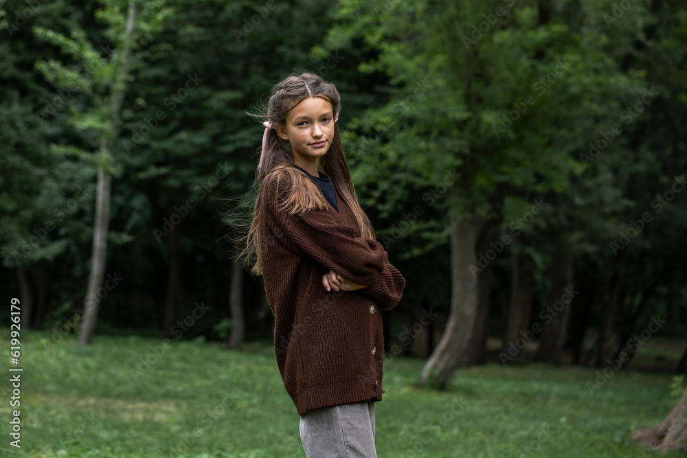 Beautiful teenage girl in a knitted brown sweater in summer park Beautiful teenage girl in a knitted brown sweater in summer park