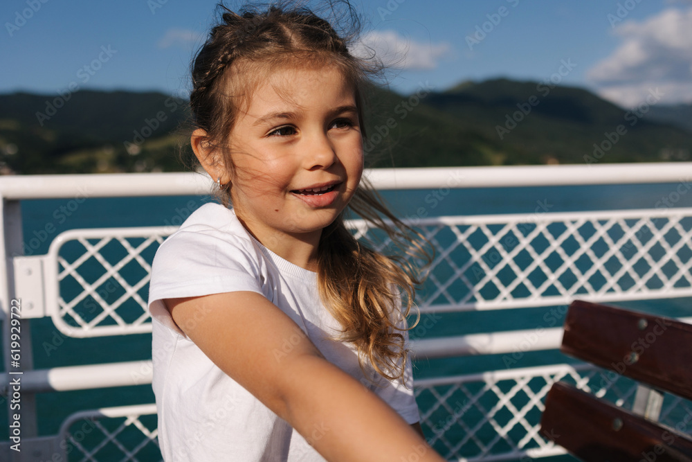 Little girl during the excursion along the lake on ship. The wind blows the hair