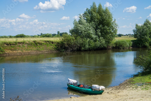 Rubber tourist kayak on the river bank with makeshift luggage. photo