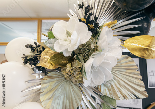 gros plan sur un bouquet de fleurs blanches et dorées en papier en guise de décoration à l'intérieur