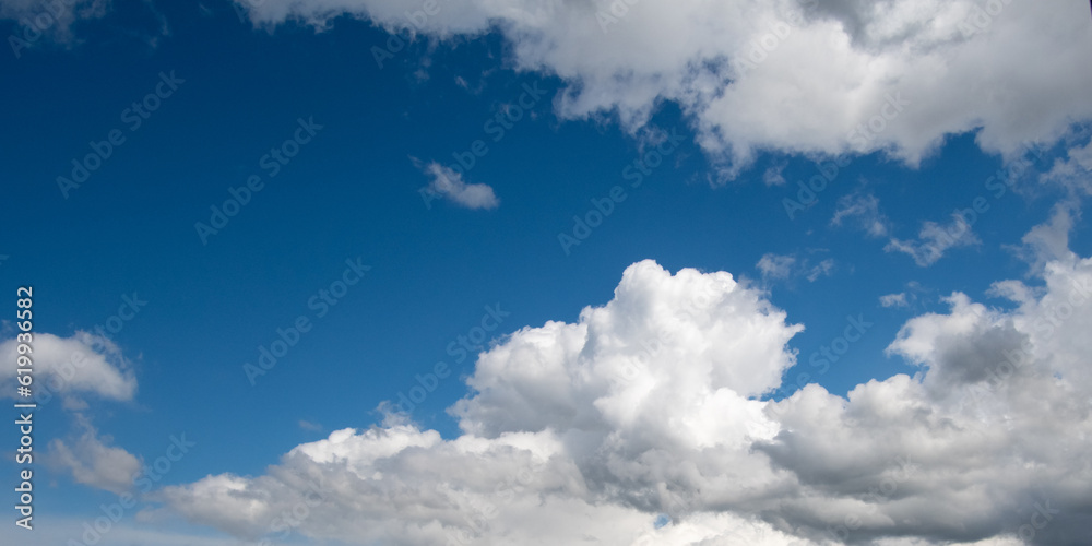 Bright blue sky with white fluffy clouds covering it and shaping a triangle-like piece of an open sky. Freedom, peaceful mood. Bright blue sky with white fluffy clouds covering it and shaping a triangle-like piece of an open sky. Freedom, peaceful mood.