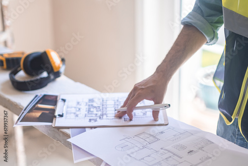 Experienced architect correcting interior project drawings of apartment before renovation process construction safety concept and equipment man in professional uniform
